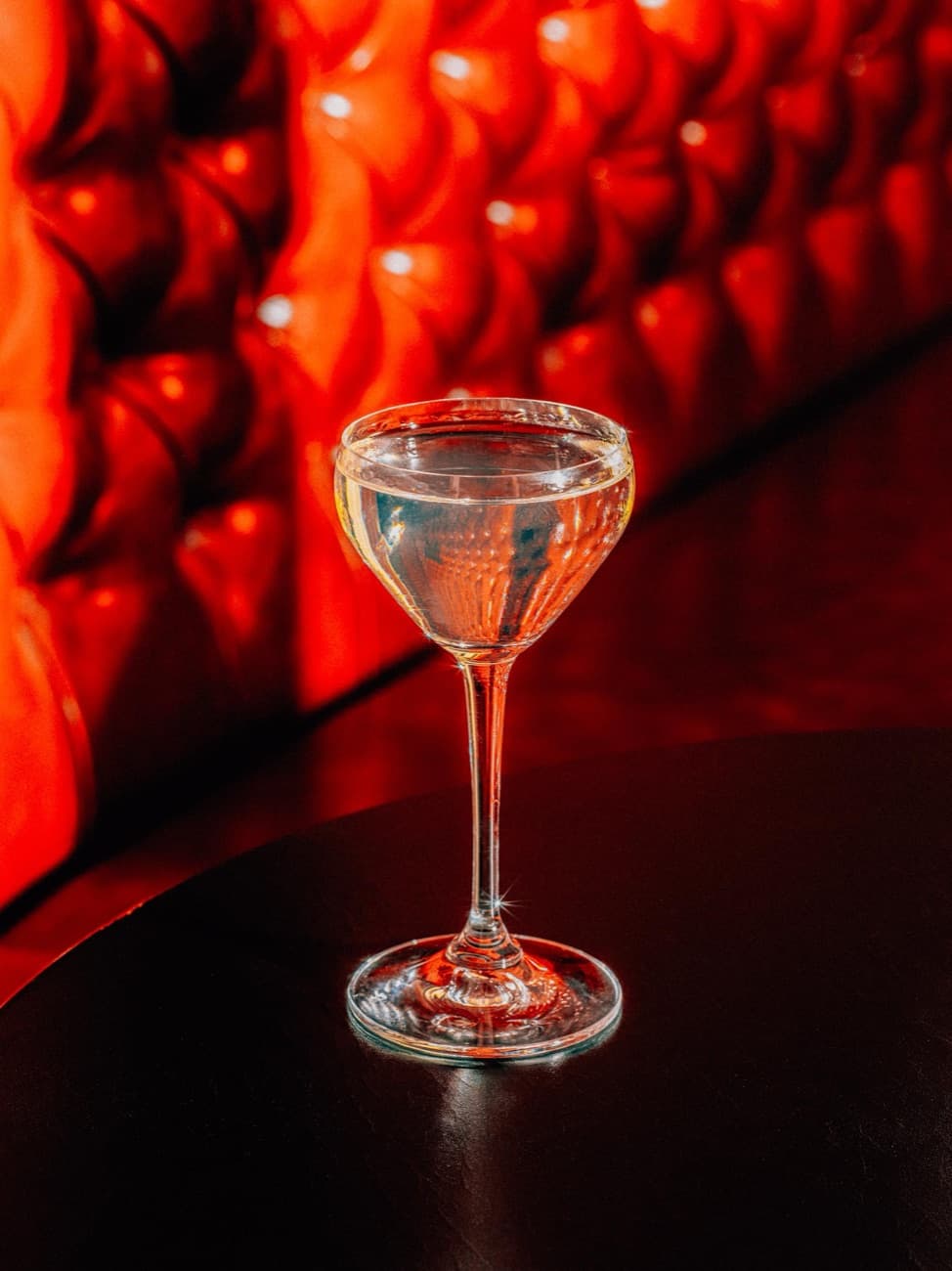 A coupe glowing under the bar's red light — the grand prize, dinner for two.